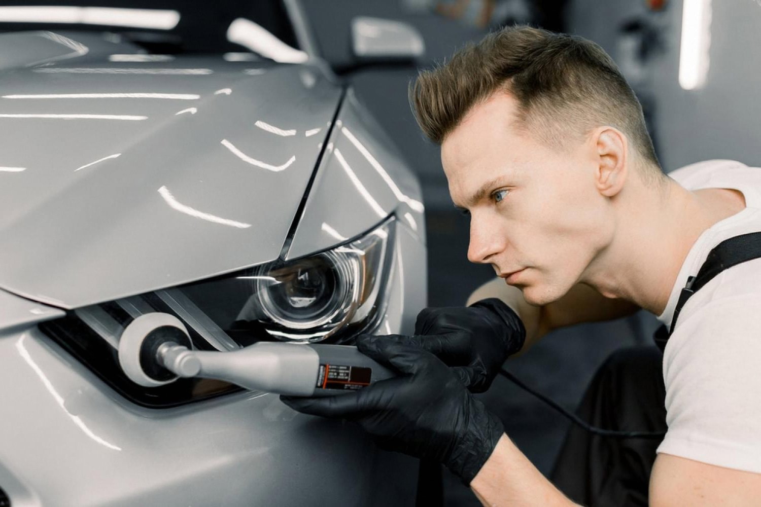 Detailer polishing a grey car headlight and paint before applying ceramic coating in the UAE