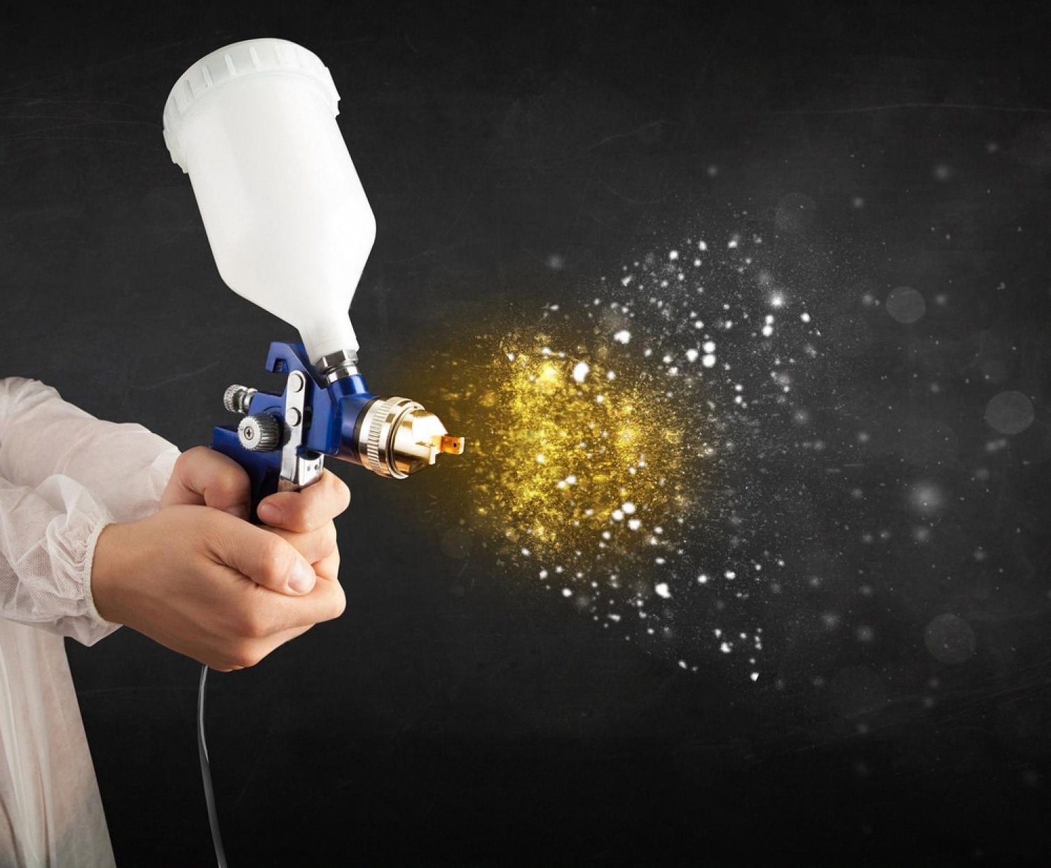 Technician holding a spray gun applying sealant used in dealer paint protection packages