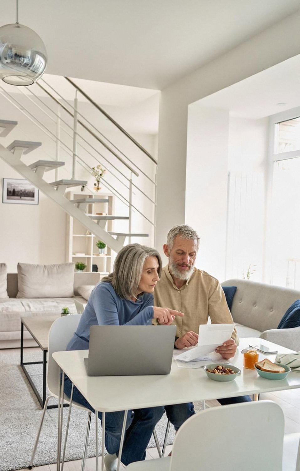 Older couple in a bright Dubai apartment reviewing a home insurance policy on a laptop