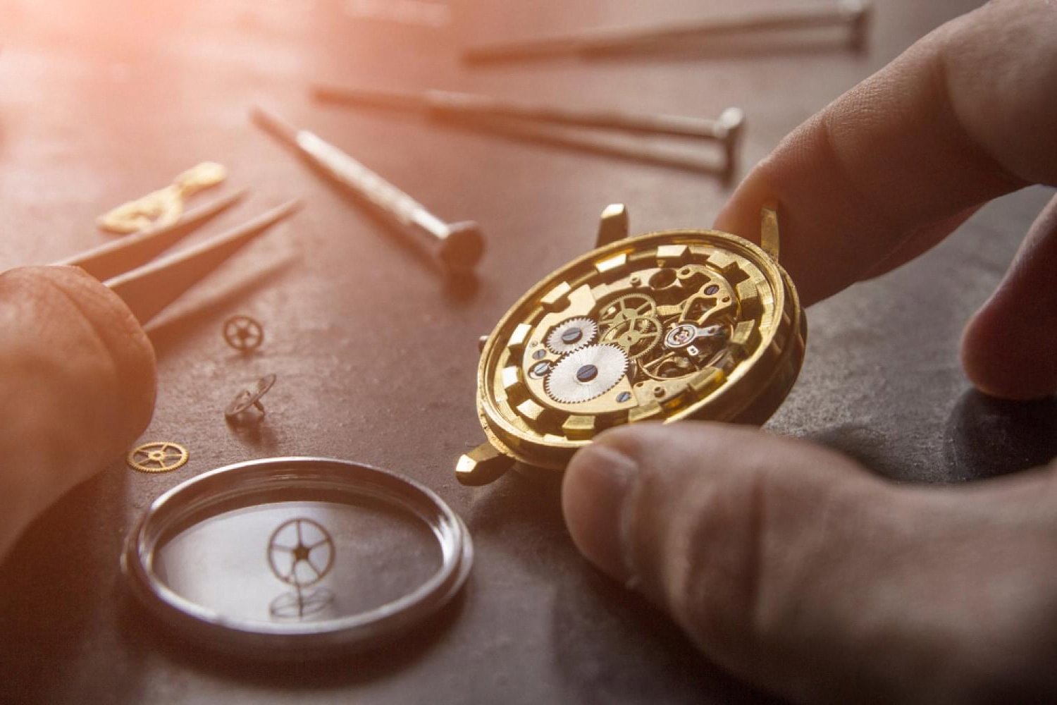 Watchmaker inspecting a mechanical watch movement on a workbench, illustrating the care a good watch safe should protect