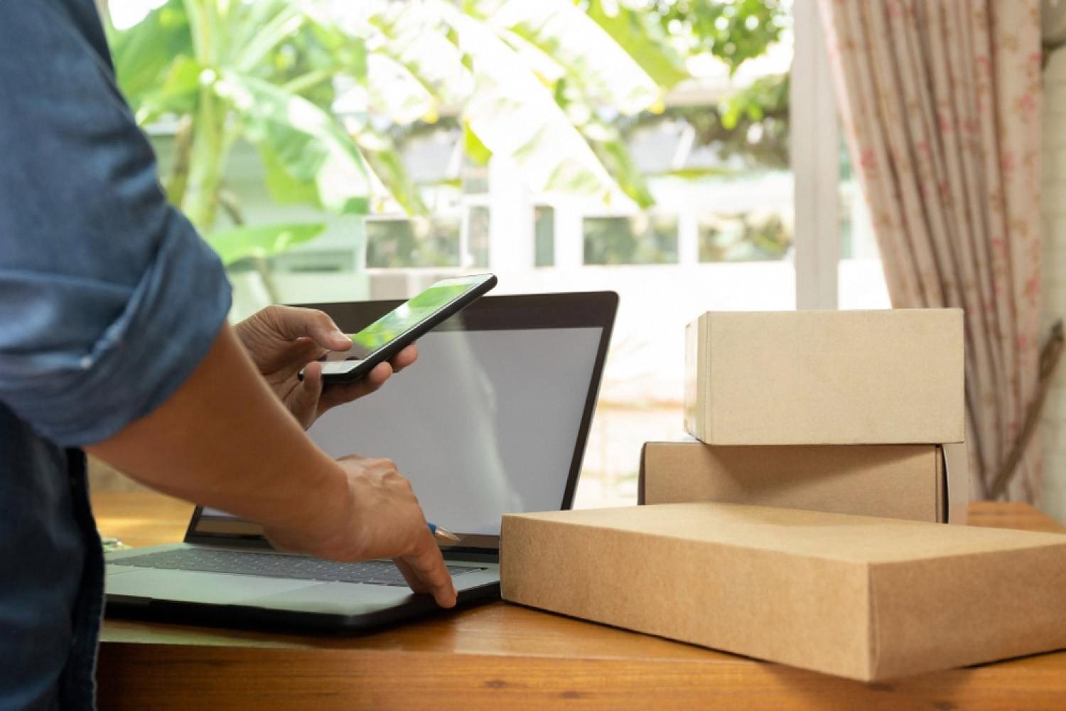Small rental operator in Dubai checking orders on a phone next to packaged inventory
